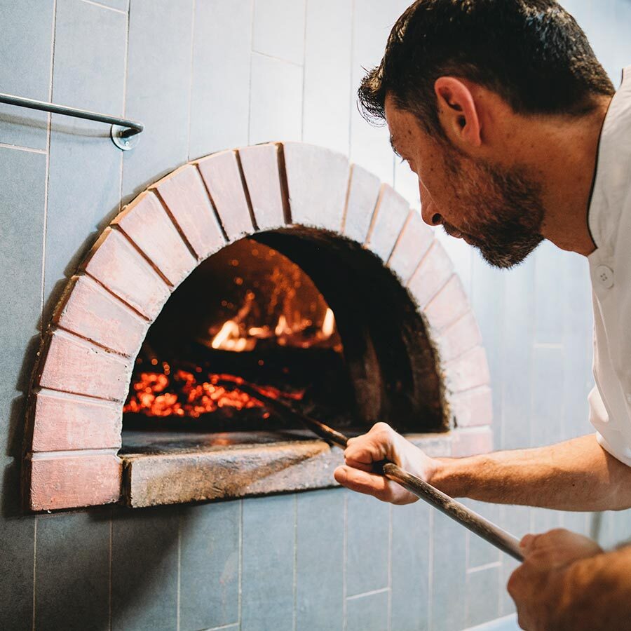 man cooking in wood fire oven
