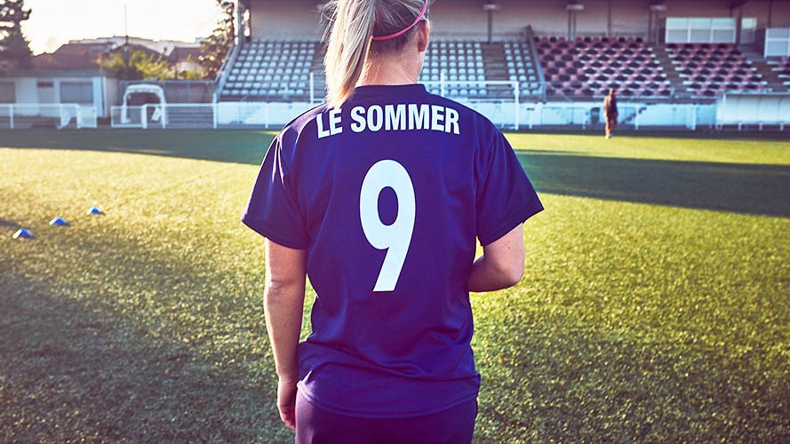 Eugenie Le Sommer wearing her jersey with the number nine on it facing the football pitch with her back faced towards the camera. 
