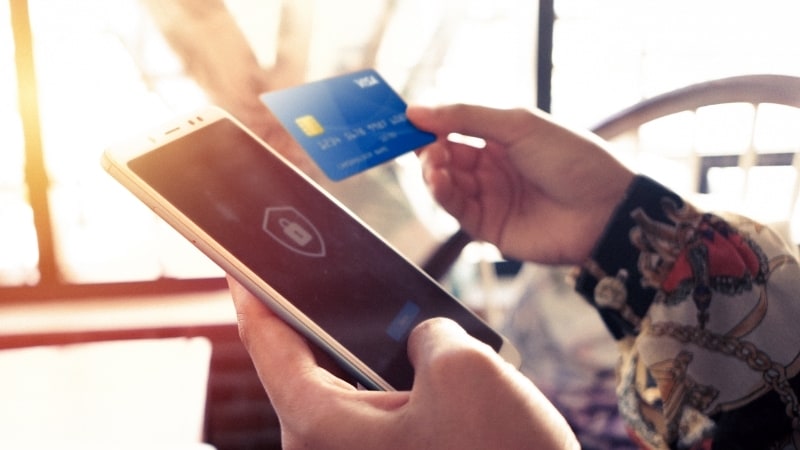 Woman completing security step to access a mobile app on her smartphone while holding a Visa card