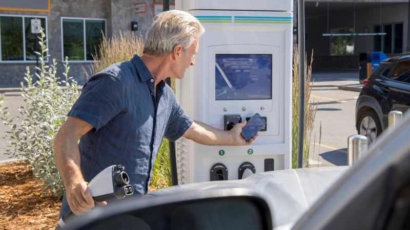 man paying at electric charge point for car